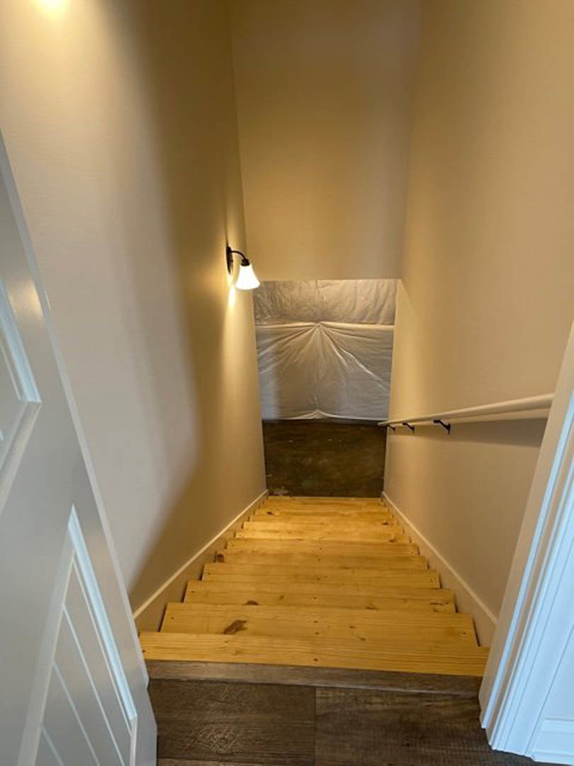 Wooden staircase with light fixture mounted on smooth white plaster wall, hardwood flooring, and simple white base molding