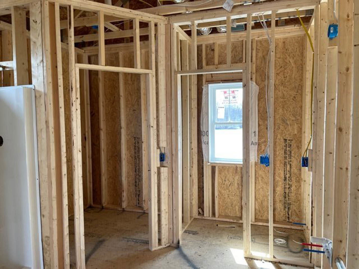 Bright room with two large windows, white walls, wooden shelf holding foil cans, exposed wood beams, and blue object with white label near window.