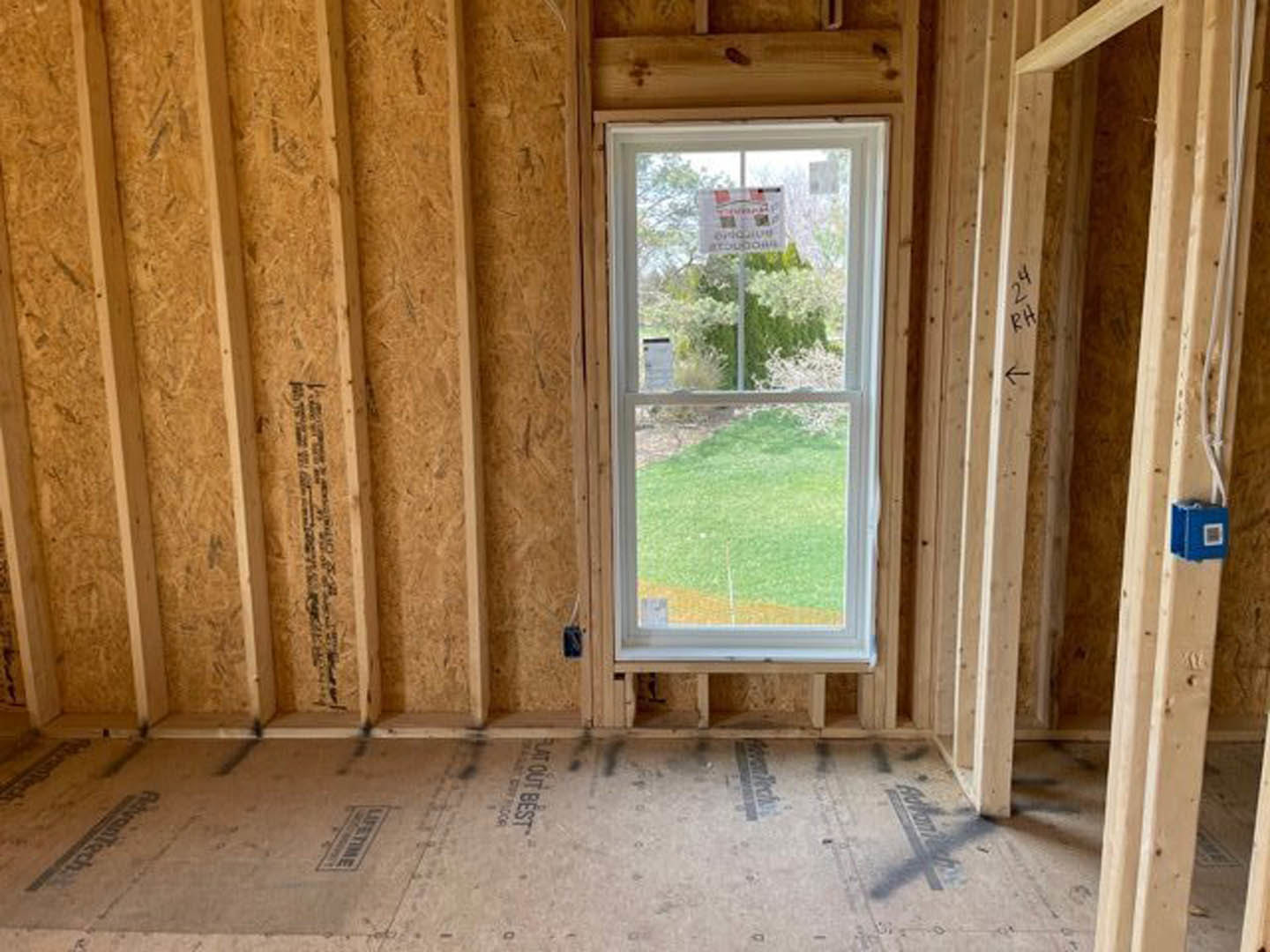 Wood-paneled walls and plank flooring in a room with a window, natural light highlighting the grain and texture of the lumber.