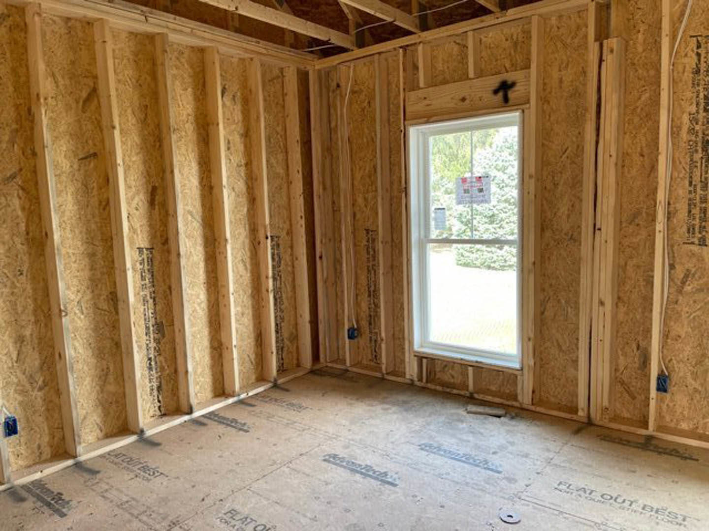 Natural wood plank walls and flooring, large window with a paper sign, exposed wooden ceiling beam