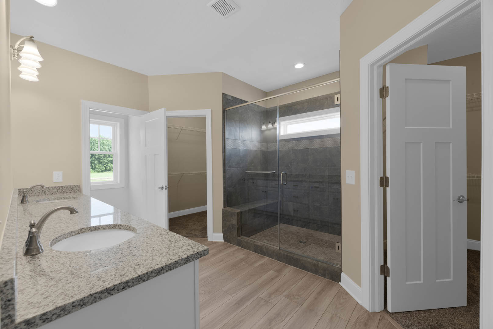 Bathroom featuring a frameless glass shower with built-in bench, white tile walls, modern vanity with rectangular sink and chrome faucet, quartz countertop, and contemporary light