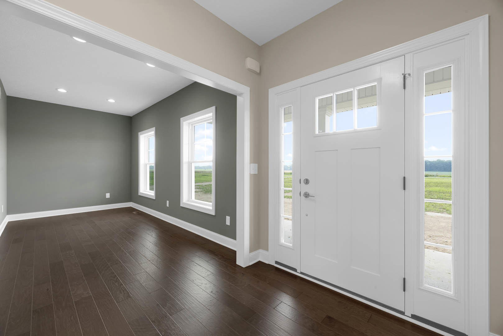 White door with glass panes, dark wood flooring, white trim, and window overlooking a grassy field
