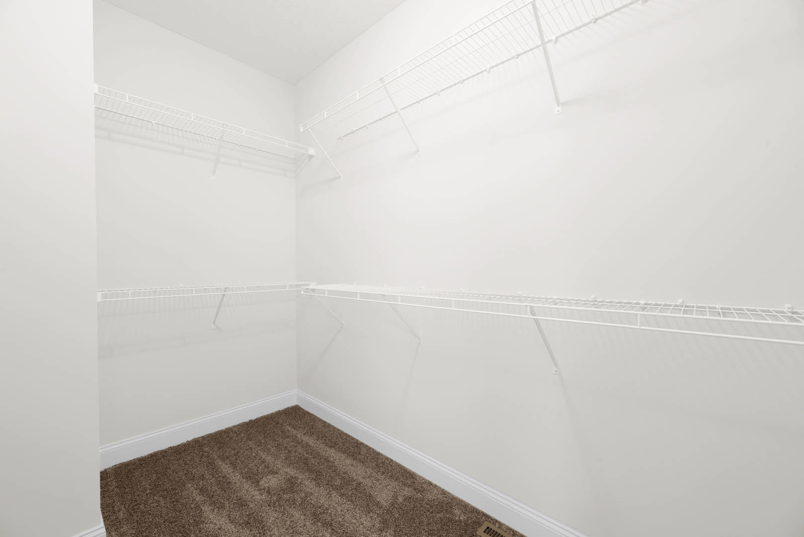 White built-in shelves against a plaster wall, brown carpet flooring, white ceiling, and a white ladder leaning on the wall in a residential room.