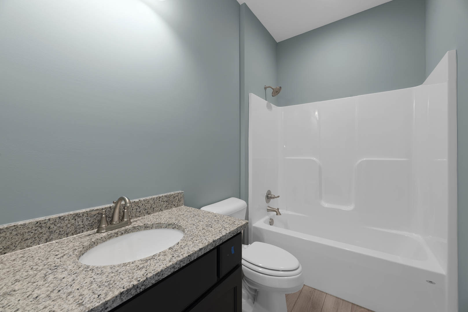 Modern bathroom with white tile walls, freestanding bathtub, undermount sink with chrome faucet, wall-mounted mirror, and closed-lid toilet