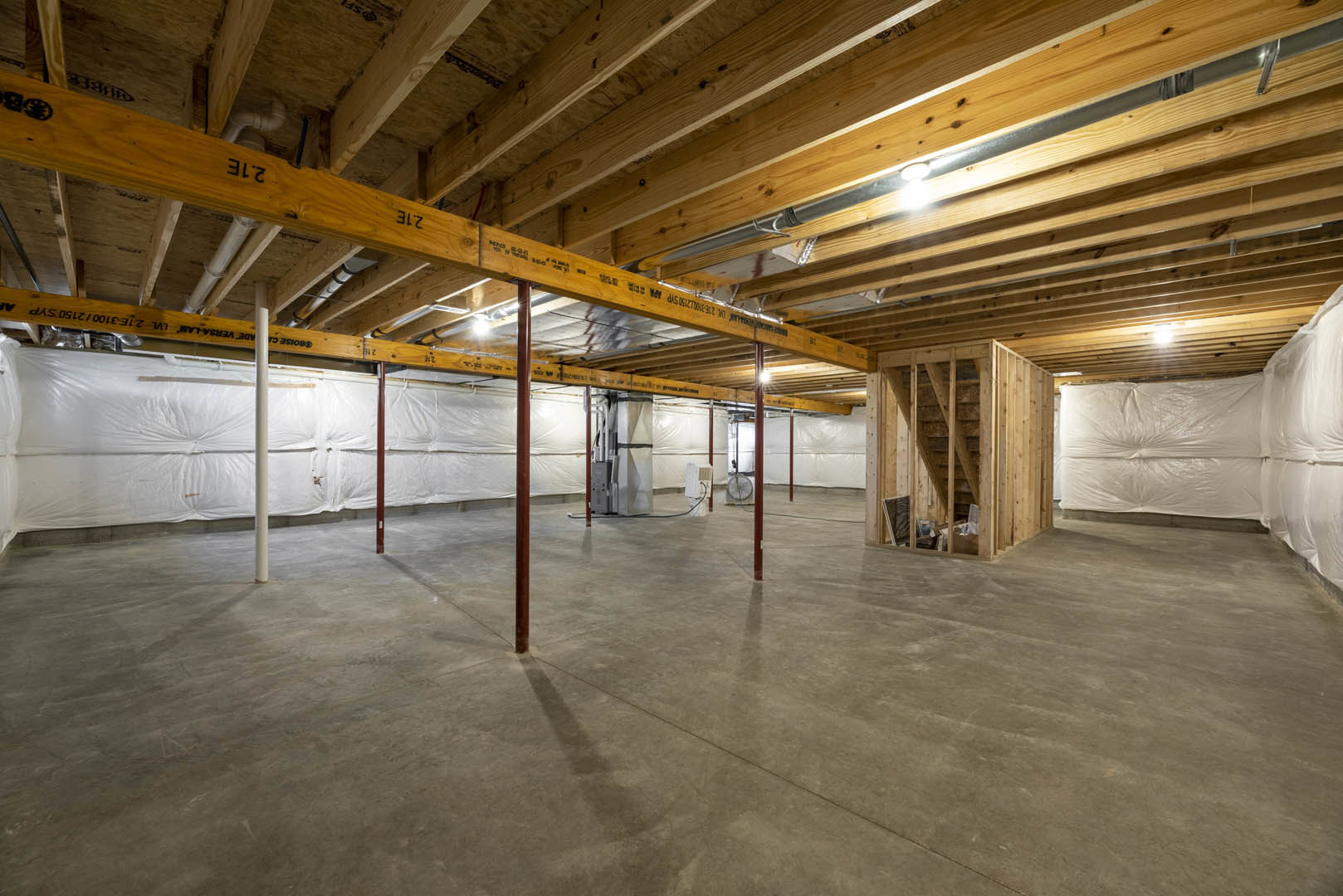 Exposed wooden ceiling beams, white walls, light-colored flooring, and a bed with a white sheet in a spacious room