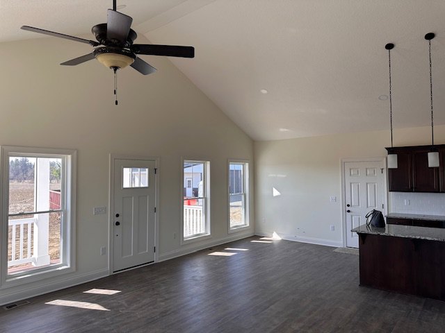 Open kitchen with wood cabinetry, stainless steel appliances, tile flooring, ceiling fan, and large windows letting in natural light.