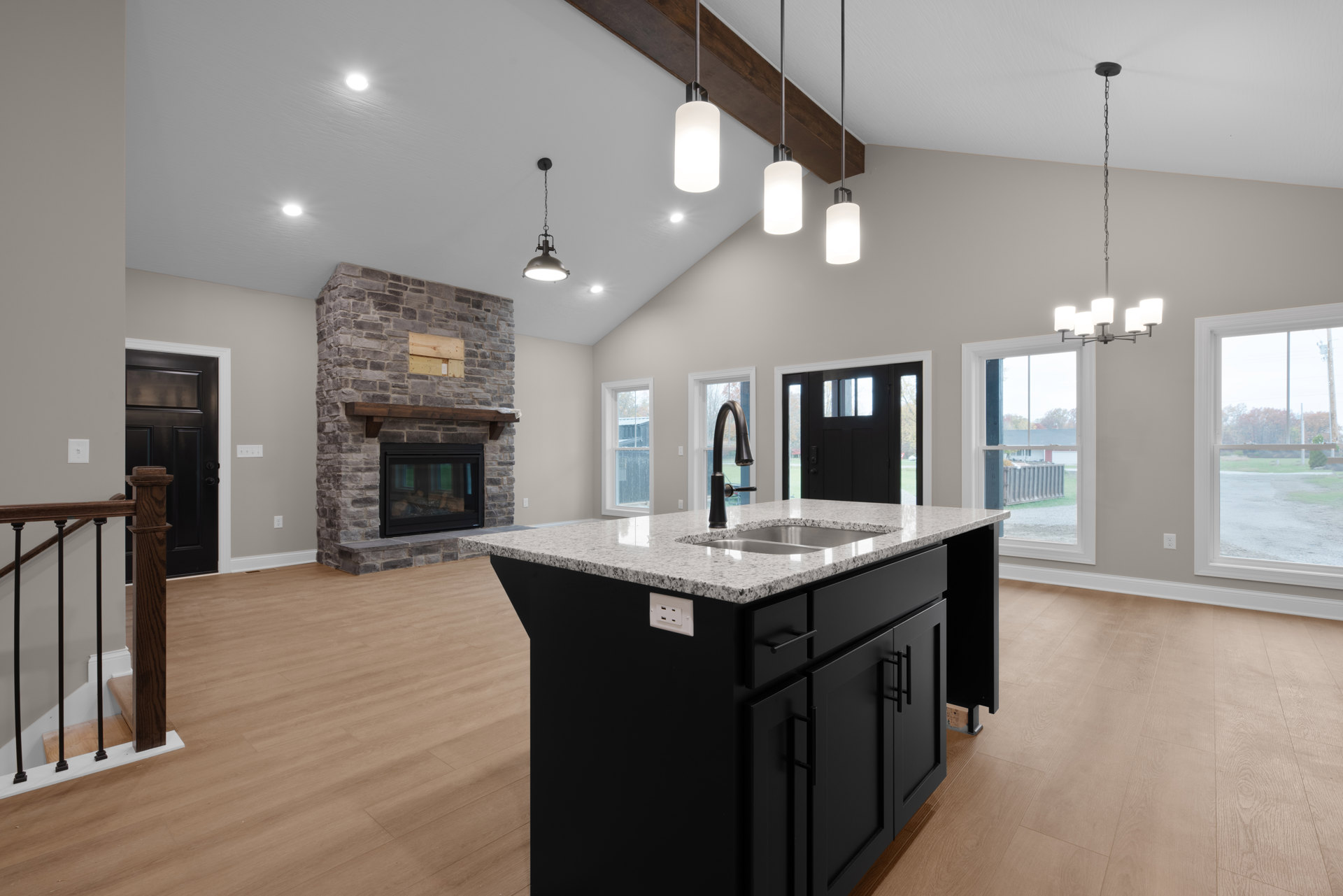 Quartz kitchen island with built-in sink, white cabinetry, stainless faucet, light wood flooring, and modern pendant lighting in a spacious open-plan interior.