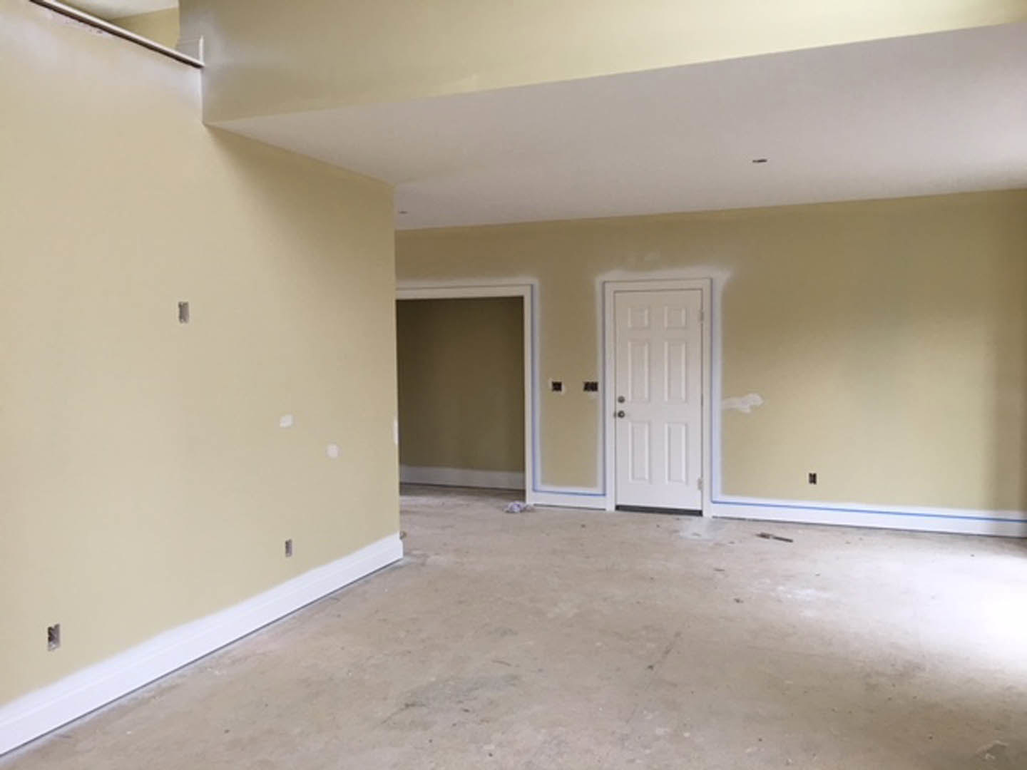 White paneled door with silver doorknob set in a smooth white wall, light-colored flooring, simple ceiling molding visible