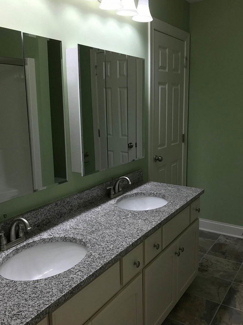 Bathroom with double sinks, white quartz countertop, chrome faucets, light gray cabinetry, and neutral tile flooring