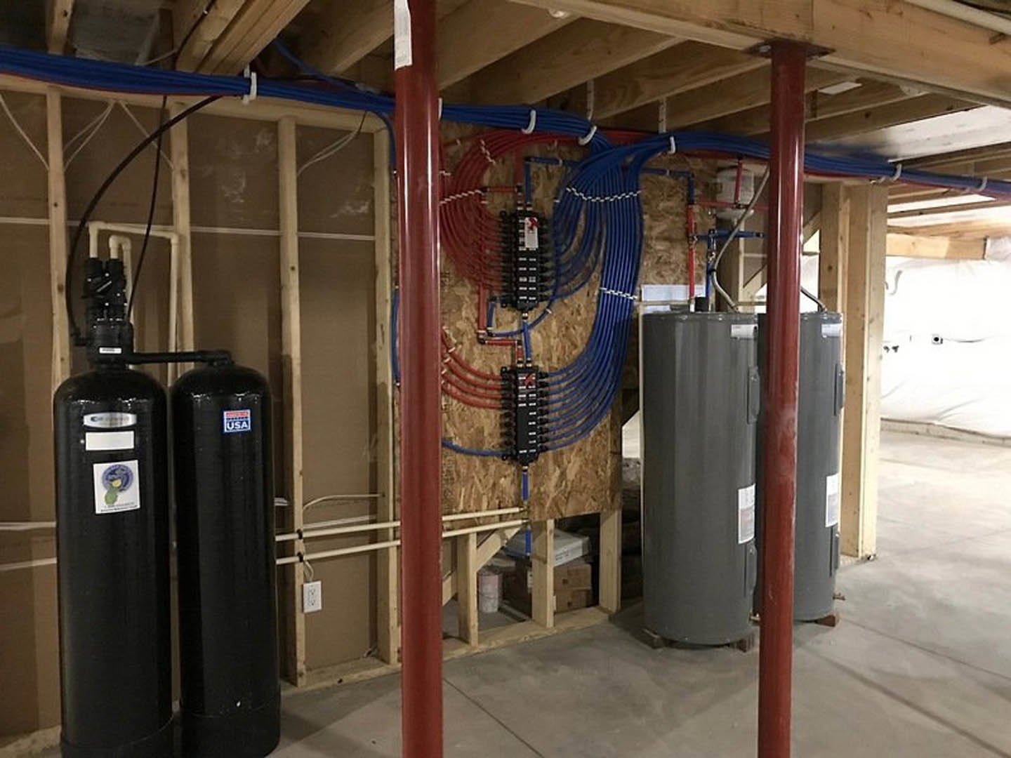 Utility room with exposed metal pipes along ceiling and walls, fire extinguisher mounted near door, concrete floor, white ceiling, industrial finishes