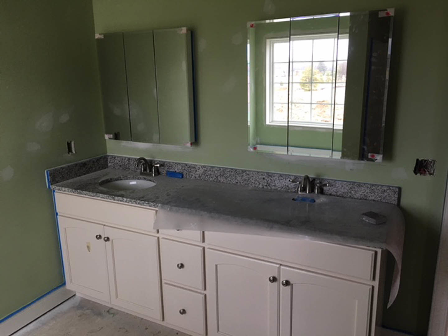 White bathroom with rectangular sink, wood cabinets, stone countertop, chrome faucet, tiled walls, and window above vanity.