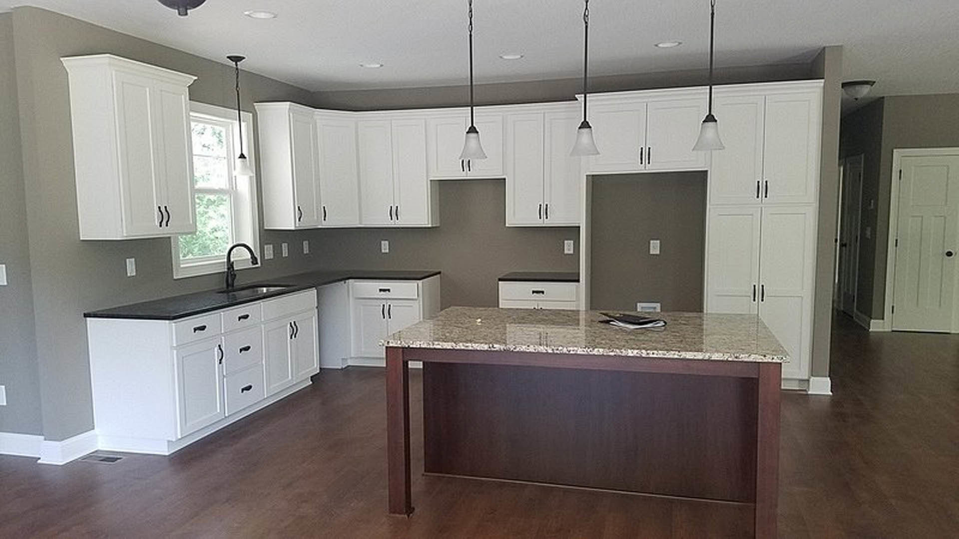 White kitchen cabinets with marble countertop, stainless steel sink, newspaper on counter, light wood flooring, and modern appliances