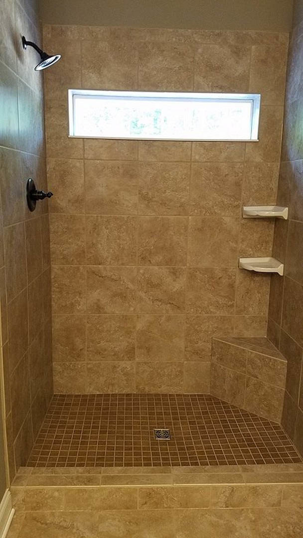 Tiled shower with a window, black-handled shower head, and glass door