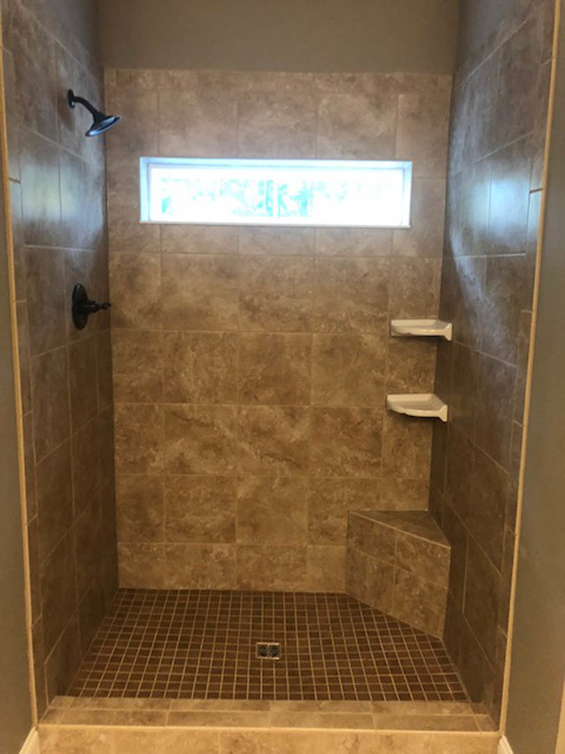 Tiled shower with window, wall-mounted shower head, tile flooring