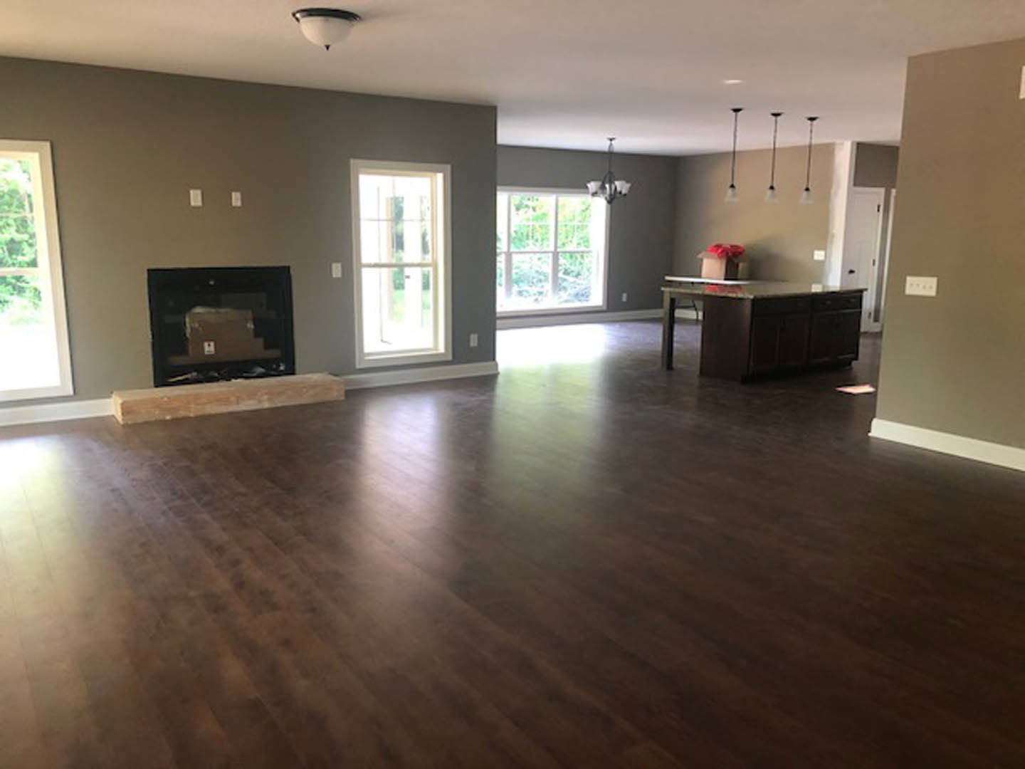 Living room with hardwood floors, stone fireplace, recessed lighting, white door with glass window, and built-in shelving with decorative boxes