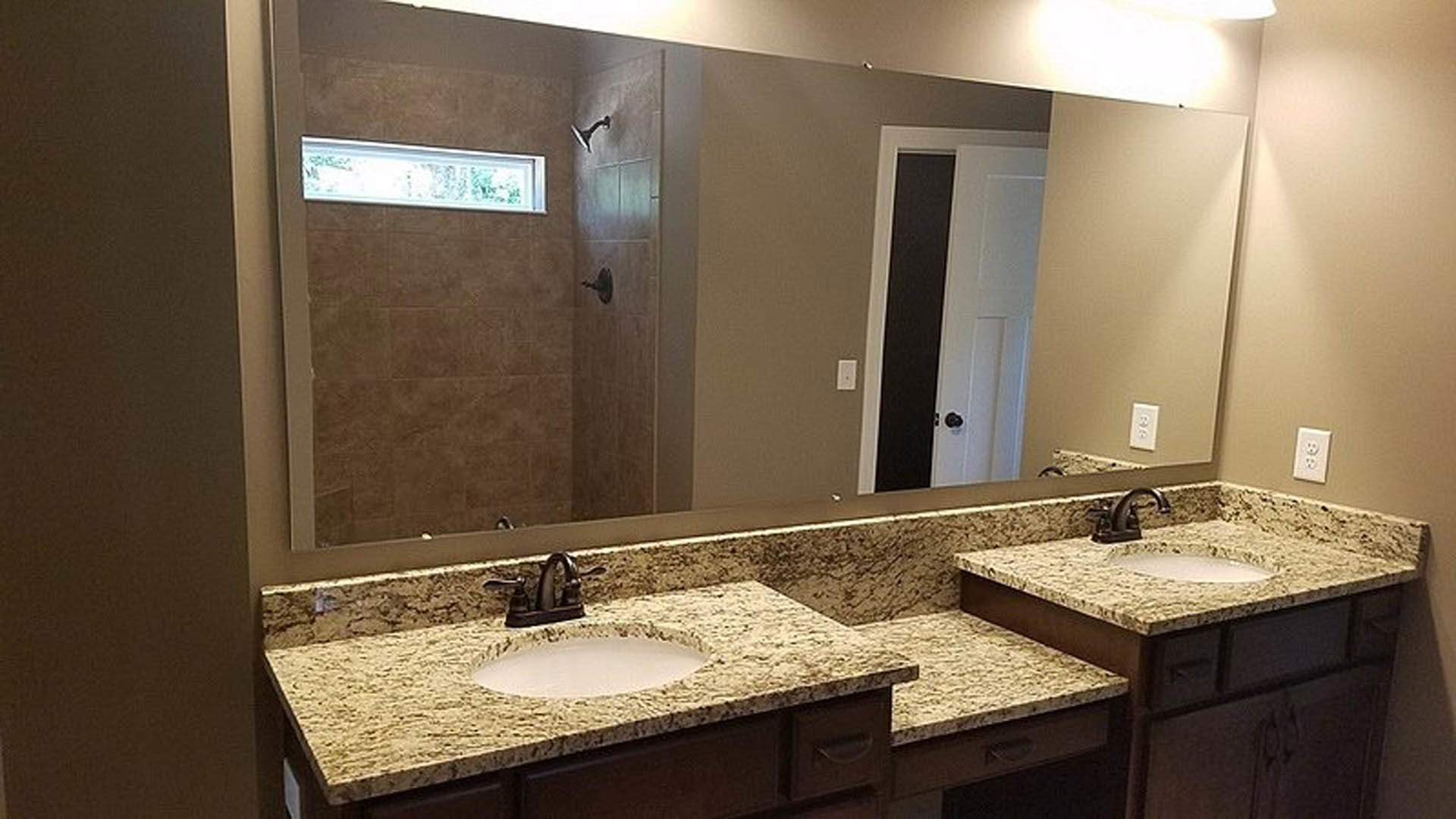 Granite countertop with undermount sink, chrome faucet, white tile backsplash, and neutral painted walls in a modern bathroom