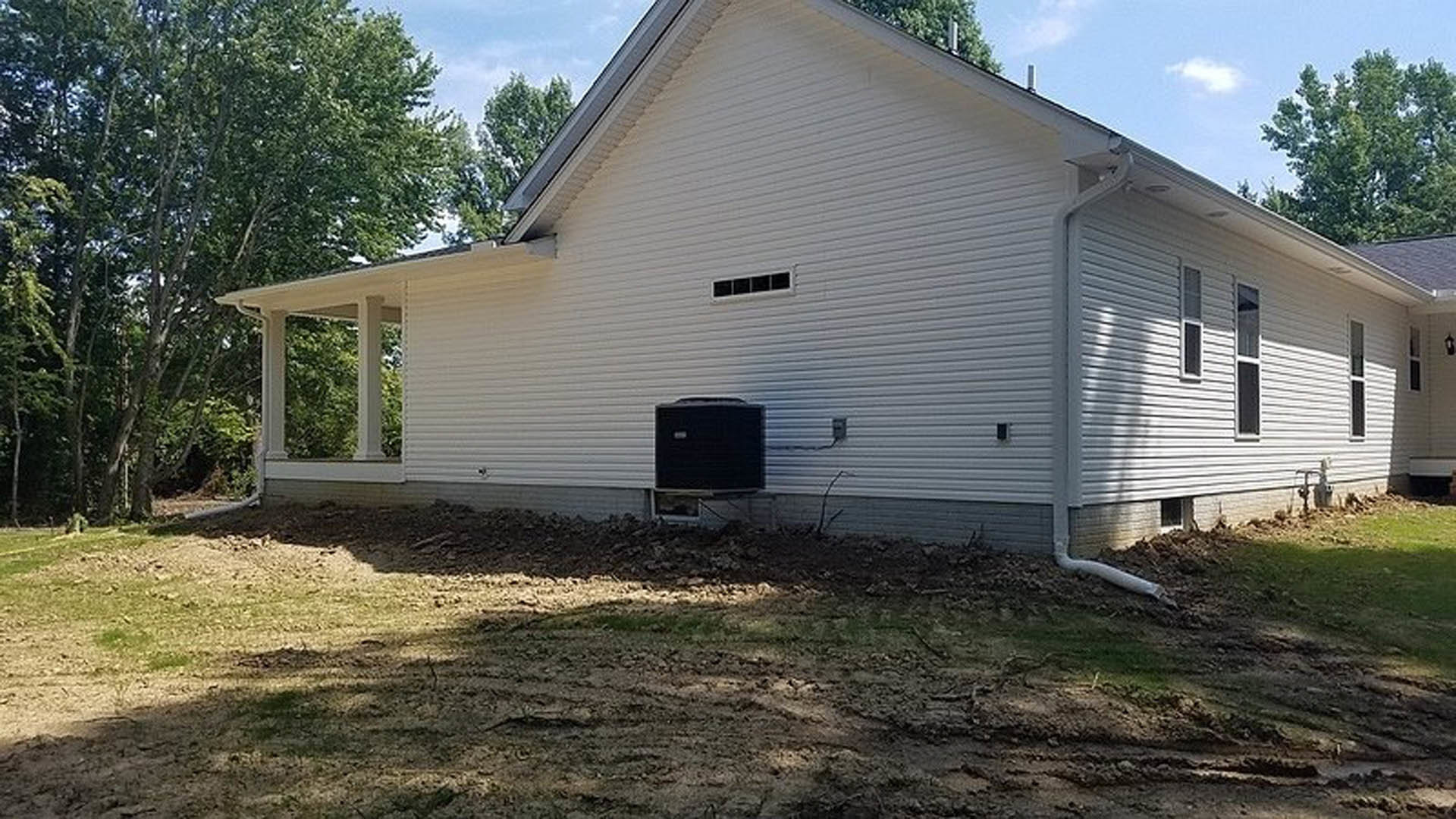 White house with smooth siding and black box mounted near entrance, dirt patch in front yard, Constitution Hall visible in background.