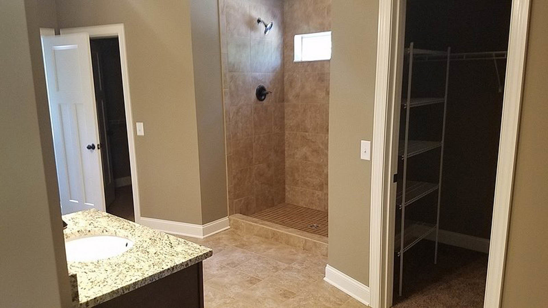 Modern bathroom featuring a glass-enclosed shower with white tile walls, a white sink set on a light wood countertop, large wall mirror, and neutral tile flooring.
