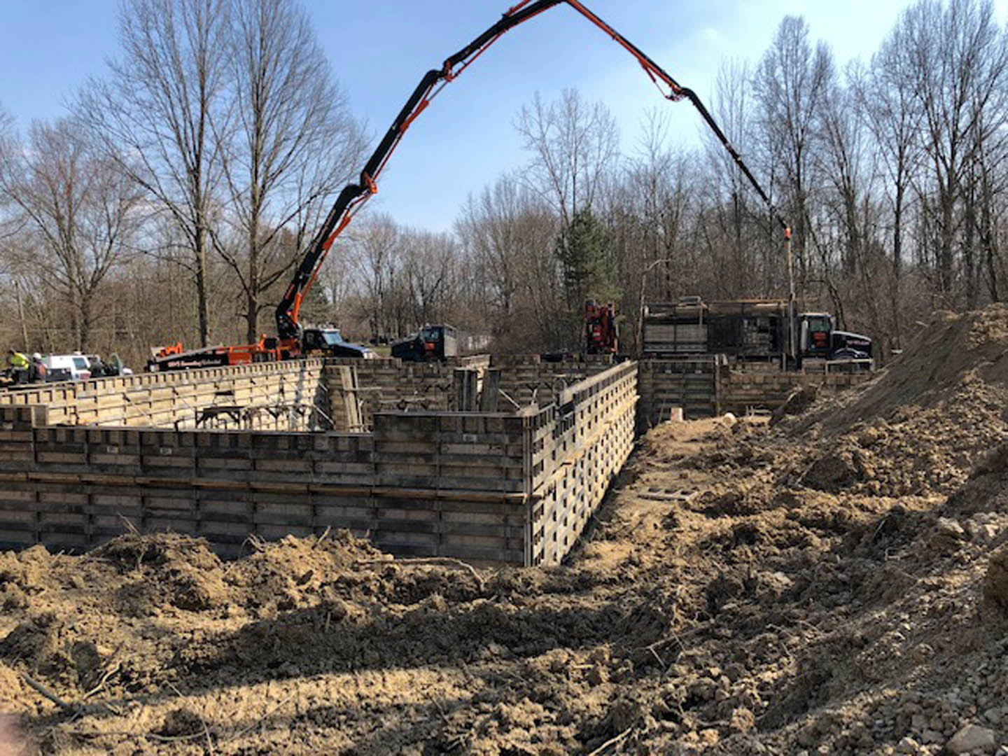 Large crane hoisting concrete foundation slab at residential construction site with exposed ground and clear sky