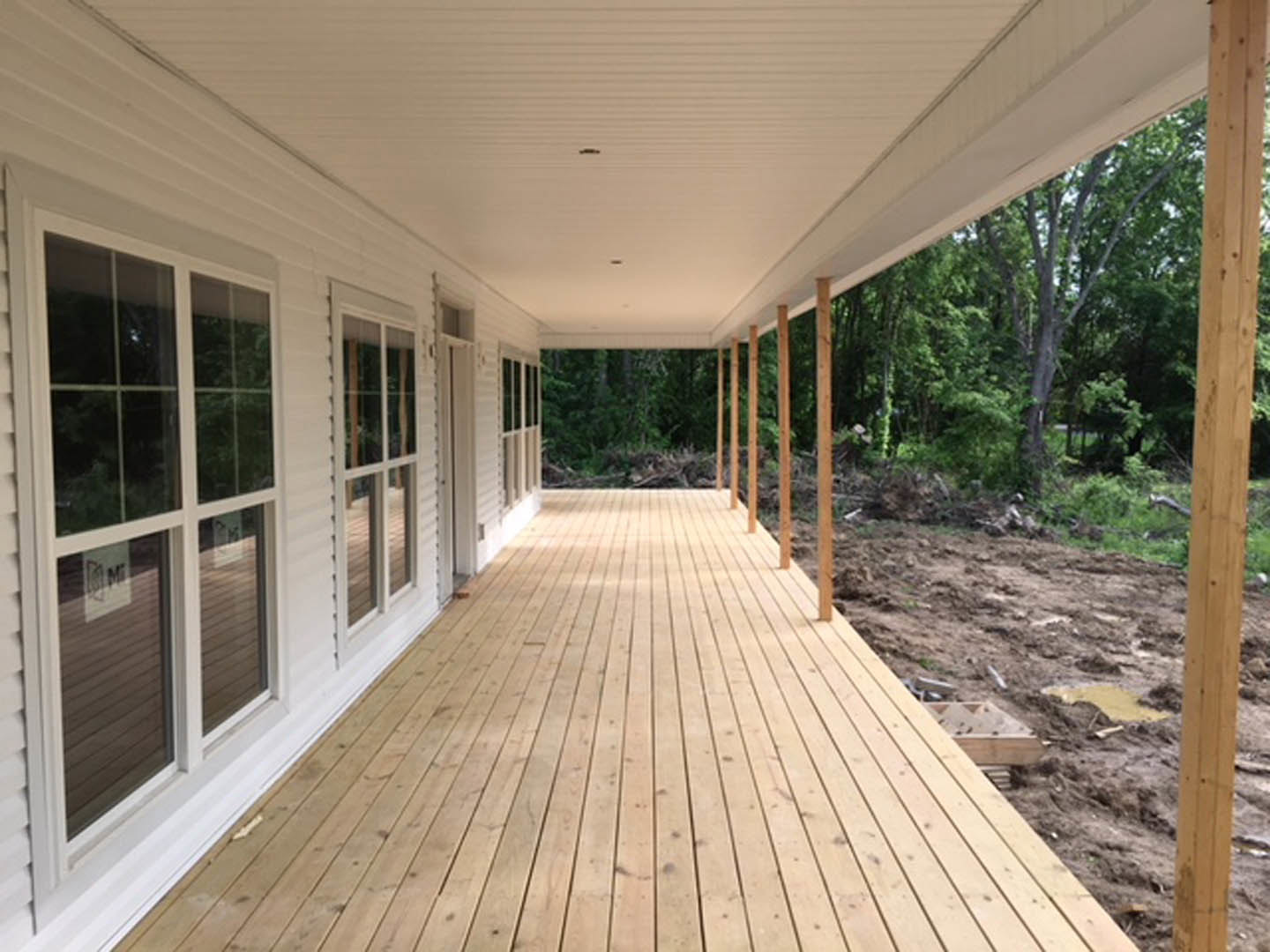 Wood deck with natural planks, white exterior wall, large windows, and a wooden post