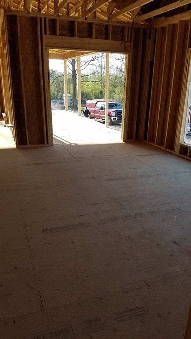 Open doorway in a partially finished room with wood flooring and built-in shelves, red truck visible outside through the window