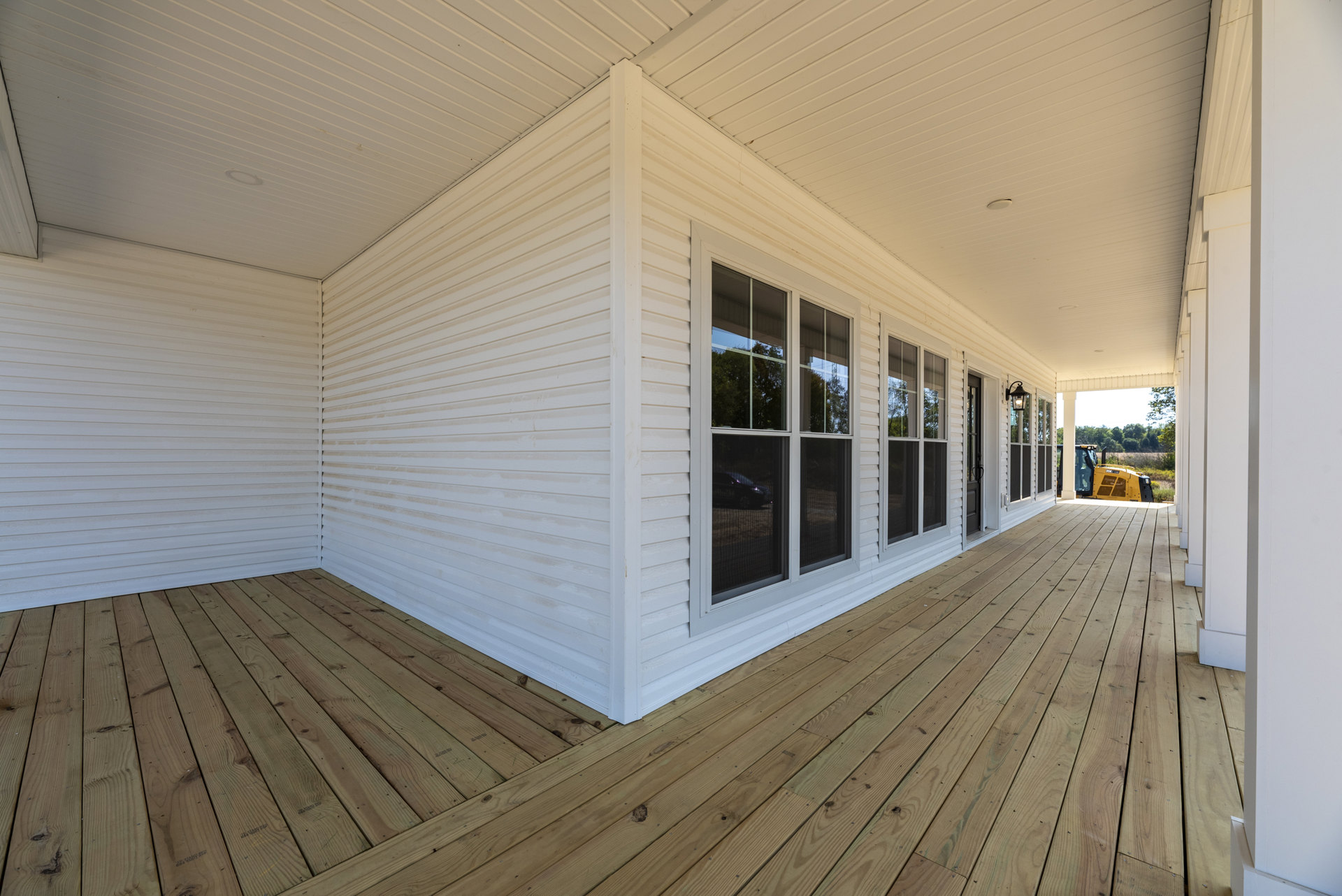 White exterior house with wooden deck, black screened window, and white walls.