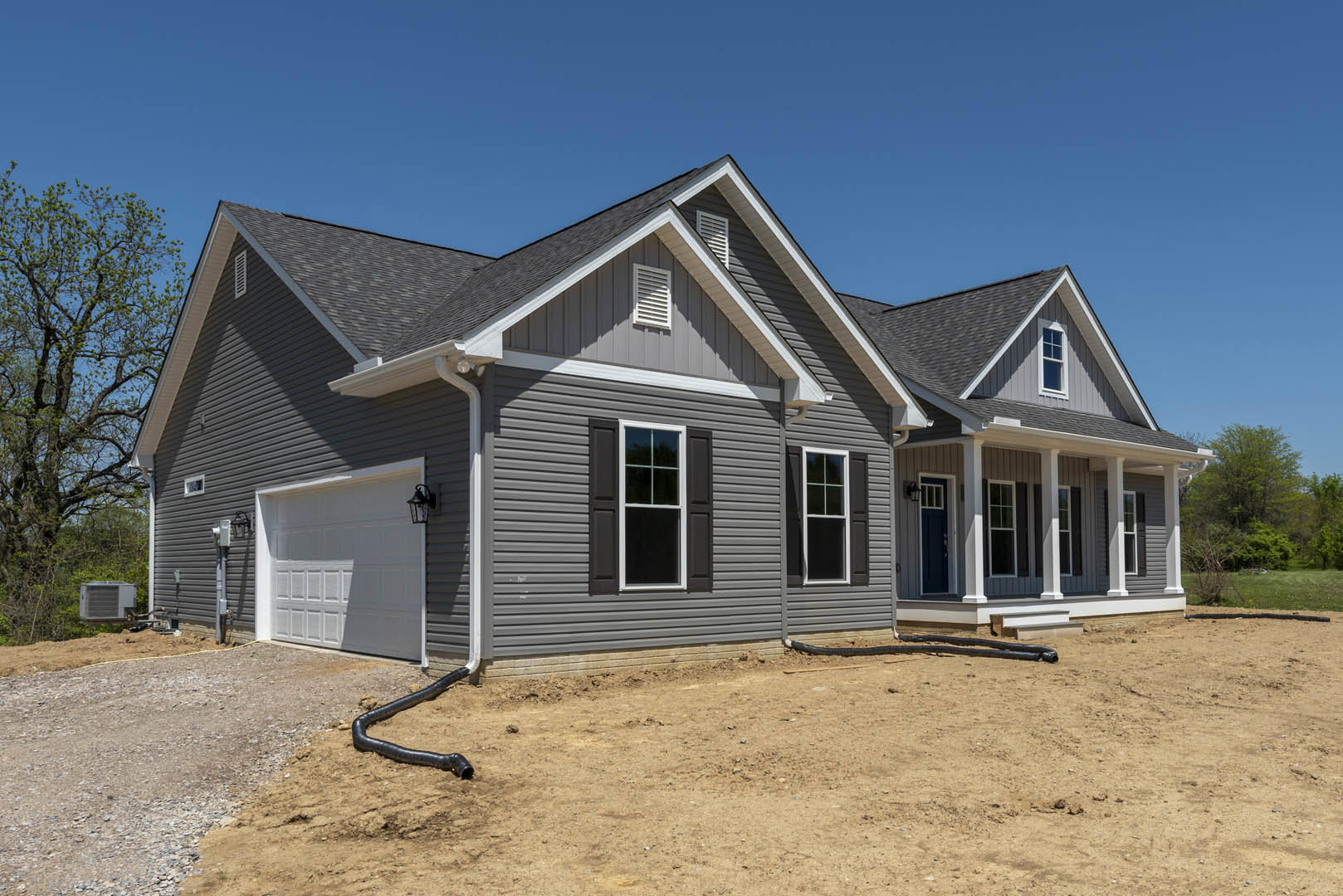 Two-story home with attached garage, paved driveway, white-framed windows, leafy tree in front yard, and Robert Frost Farm visible in the background.
