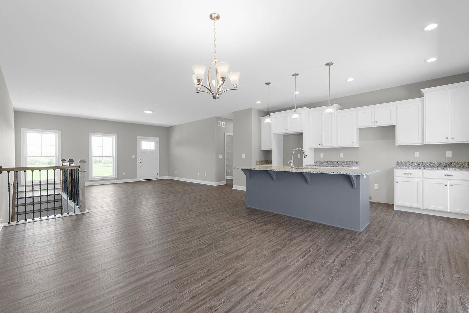 Spacious kitchen with white cabinets, marble countertops, wood flooring, central island, and large window overlooking grassy field