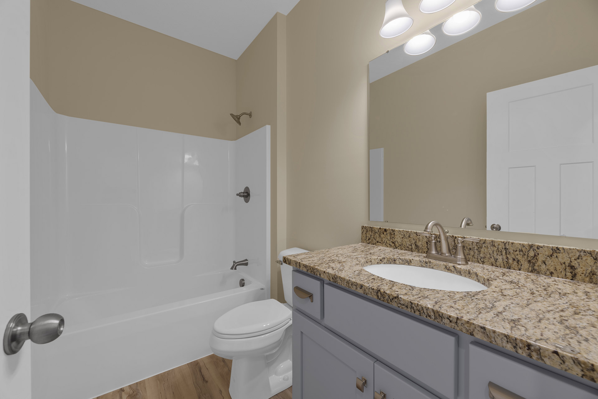Modern bathroom featuring a freestanding bathtub, white porcelain sink with chrome faucet, wall-mounted mirror above a stone countertop, white toilet with closed lid