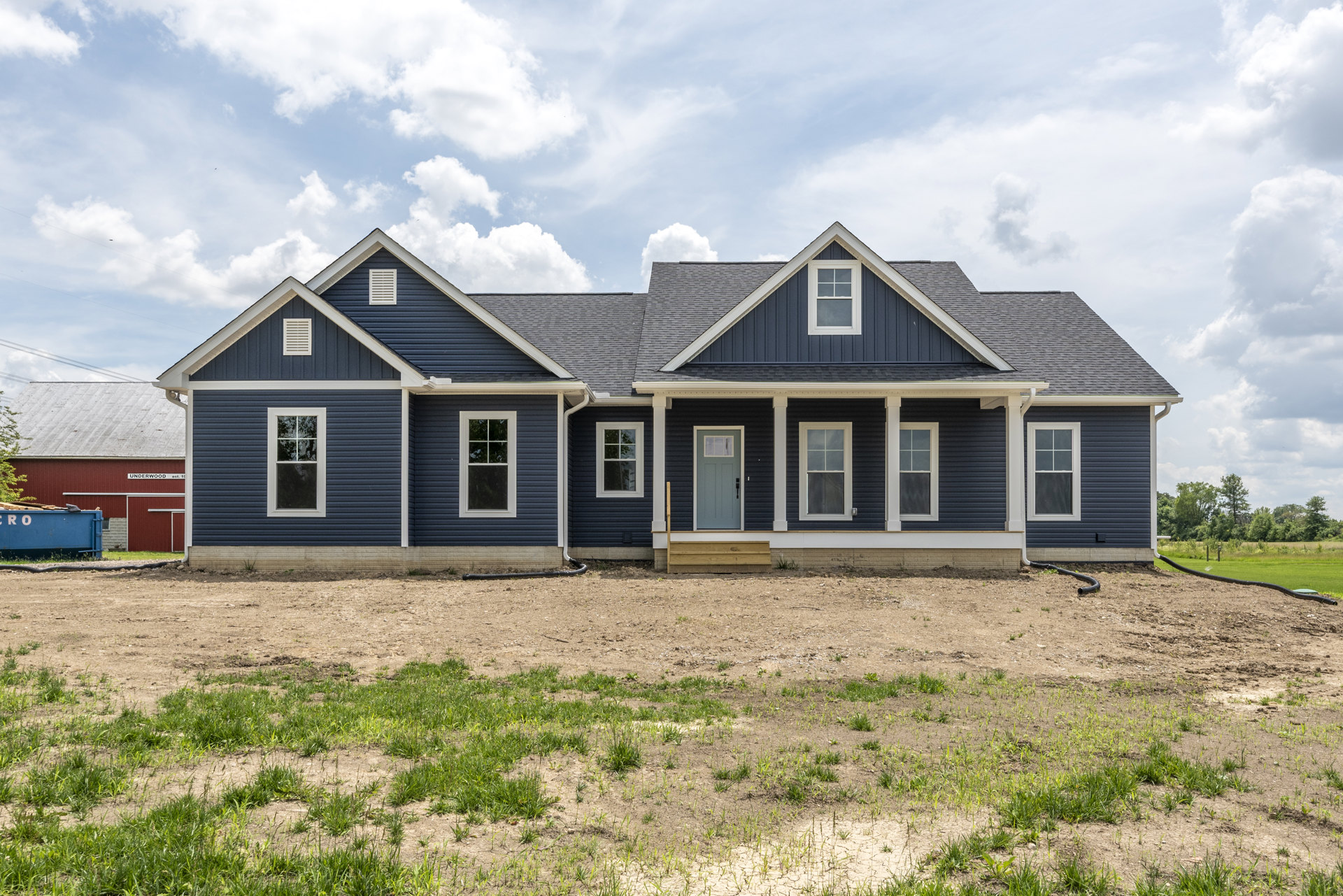 Two-story house with blue front door, white trim, large windows, and expansive green lawn