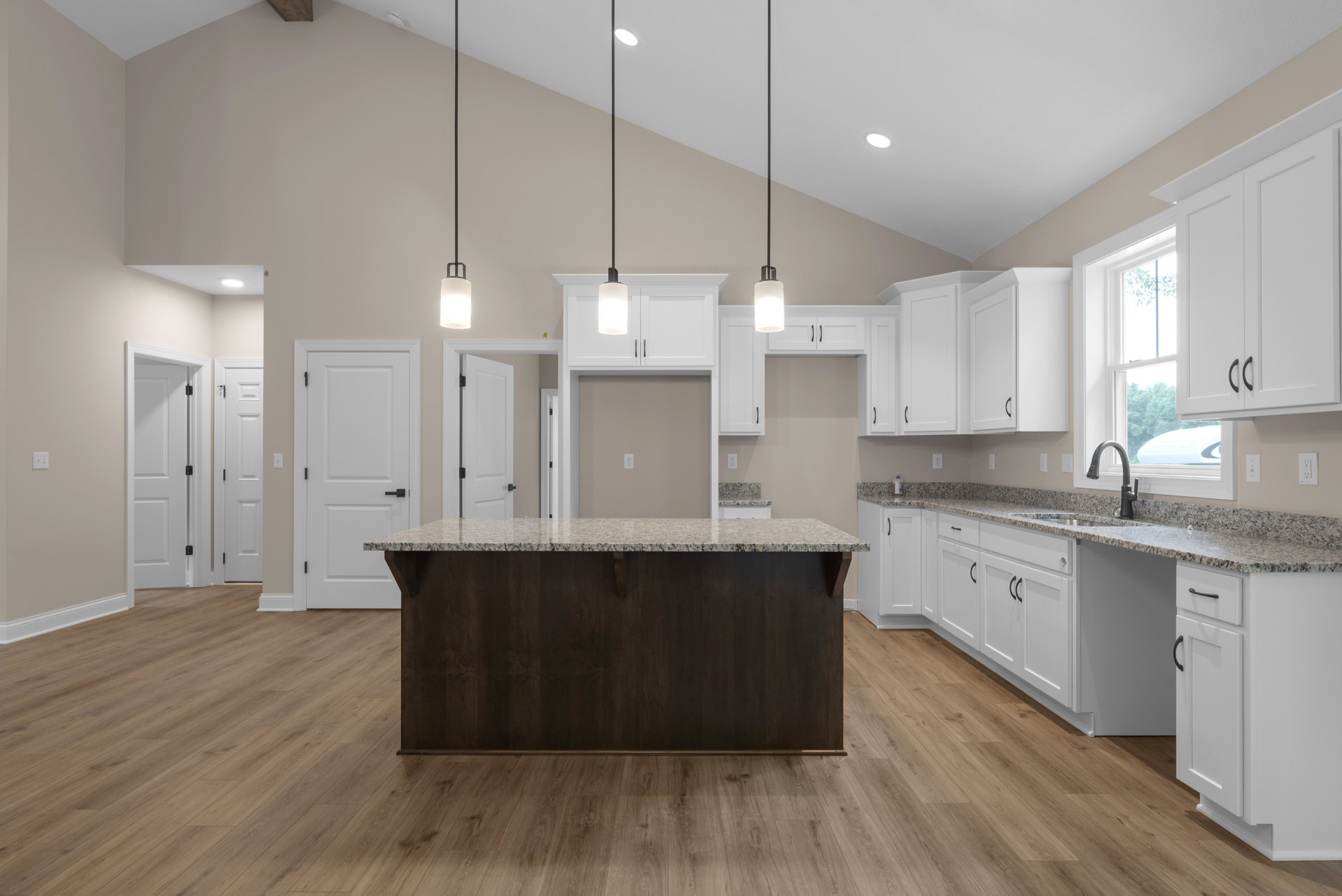 Kitchen with white shaker cabinets, large wood-surface island, black hardware, wood flooring, dark accent wall, and pendant lighting