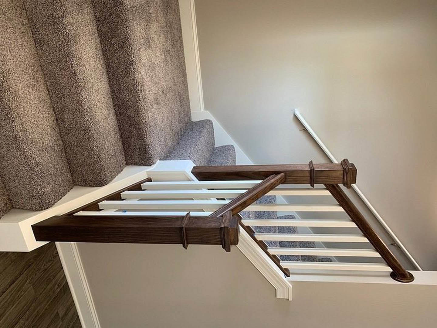 Carpeted staircase with white risers and brown wooden railing, plaster walls, and neutral interior finishes