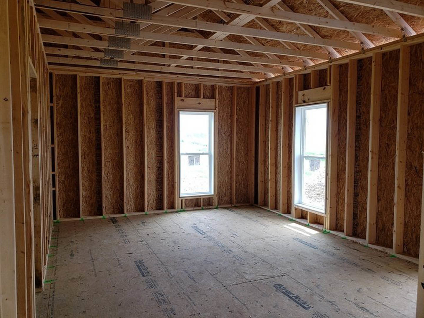 Living room with exposed wood ceiling beams, large windows, light-colored walls, and hardwood flooring