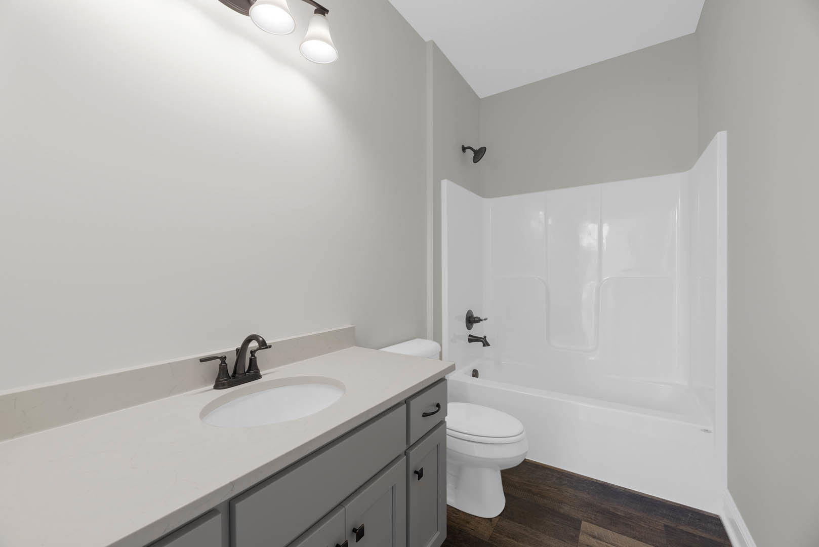 White freestanding bathtub beside a white sink and cabinet, tile flooring, chrome faucet, and closed toilet seat in a modern bathroom.