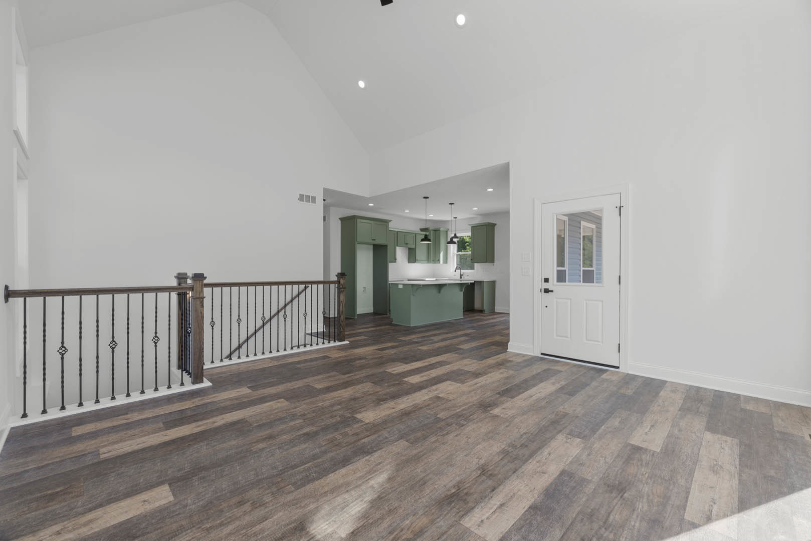 Wood flooring throughout room, white door with glass window, staircase with wooden steps and handrail, plaster walls, green rectangular object with white surface