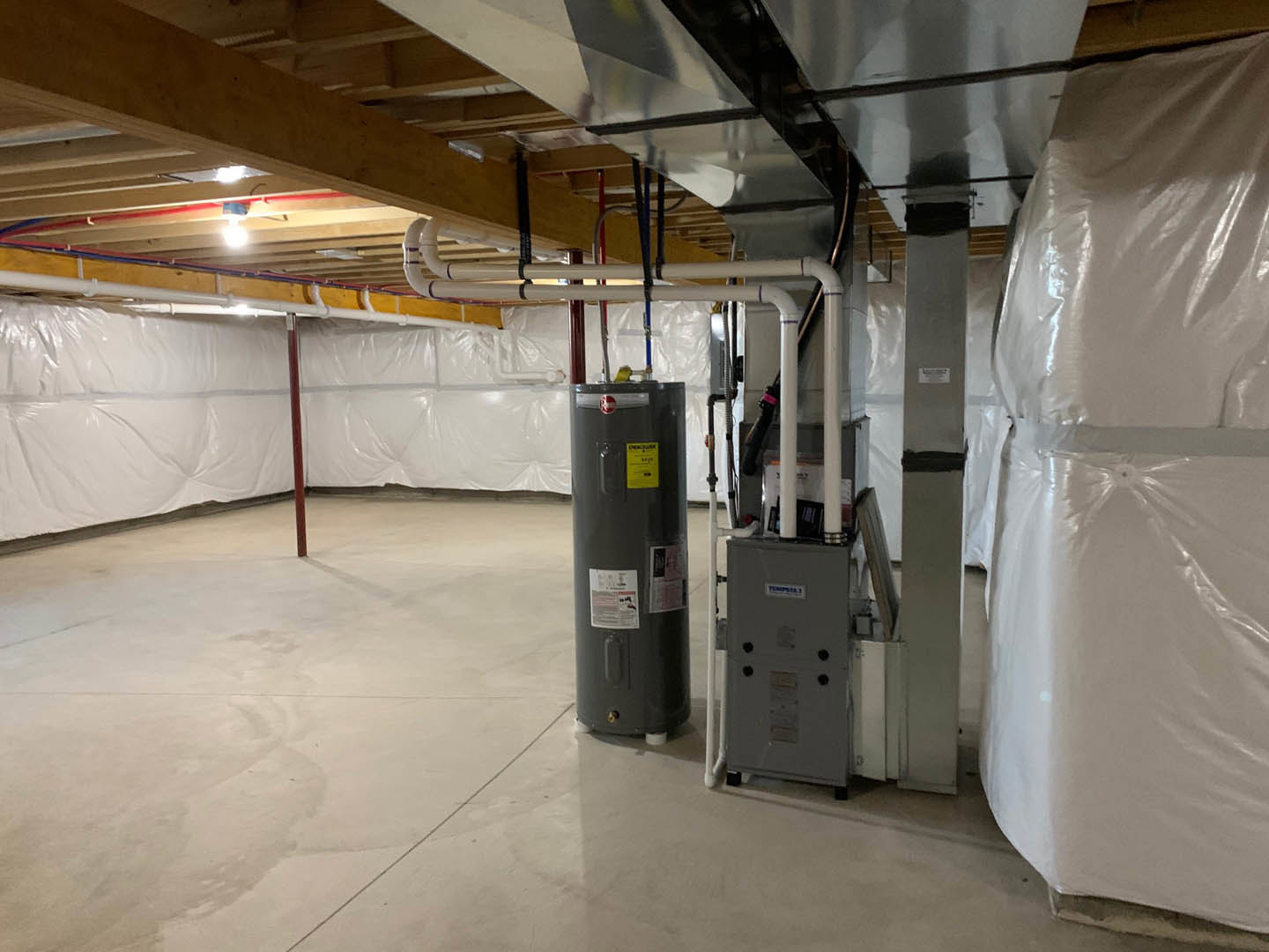 Spacious interior with white walls, grey steel tank, exposed pipes, and heater on concrete floor