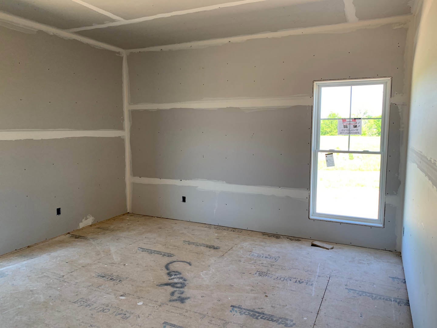 White plaster walls, large window with a sign, light-colored flooring featuring black text, ceiling with recessed lighting, subtle cloud-shaped decor on wall