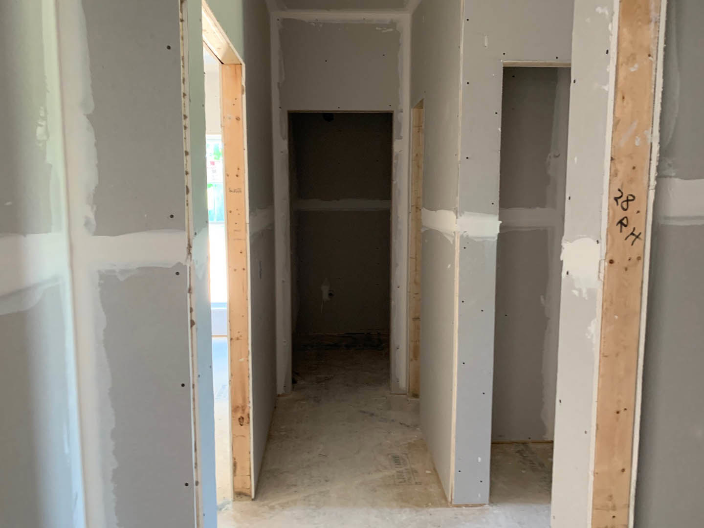 Hallway with plaster walls, wood flooring, and a doorway leading to a closed door; built-in shelf recessed into the wall.