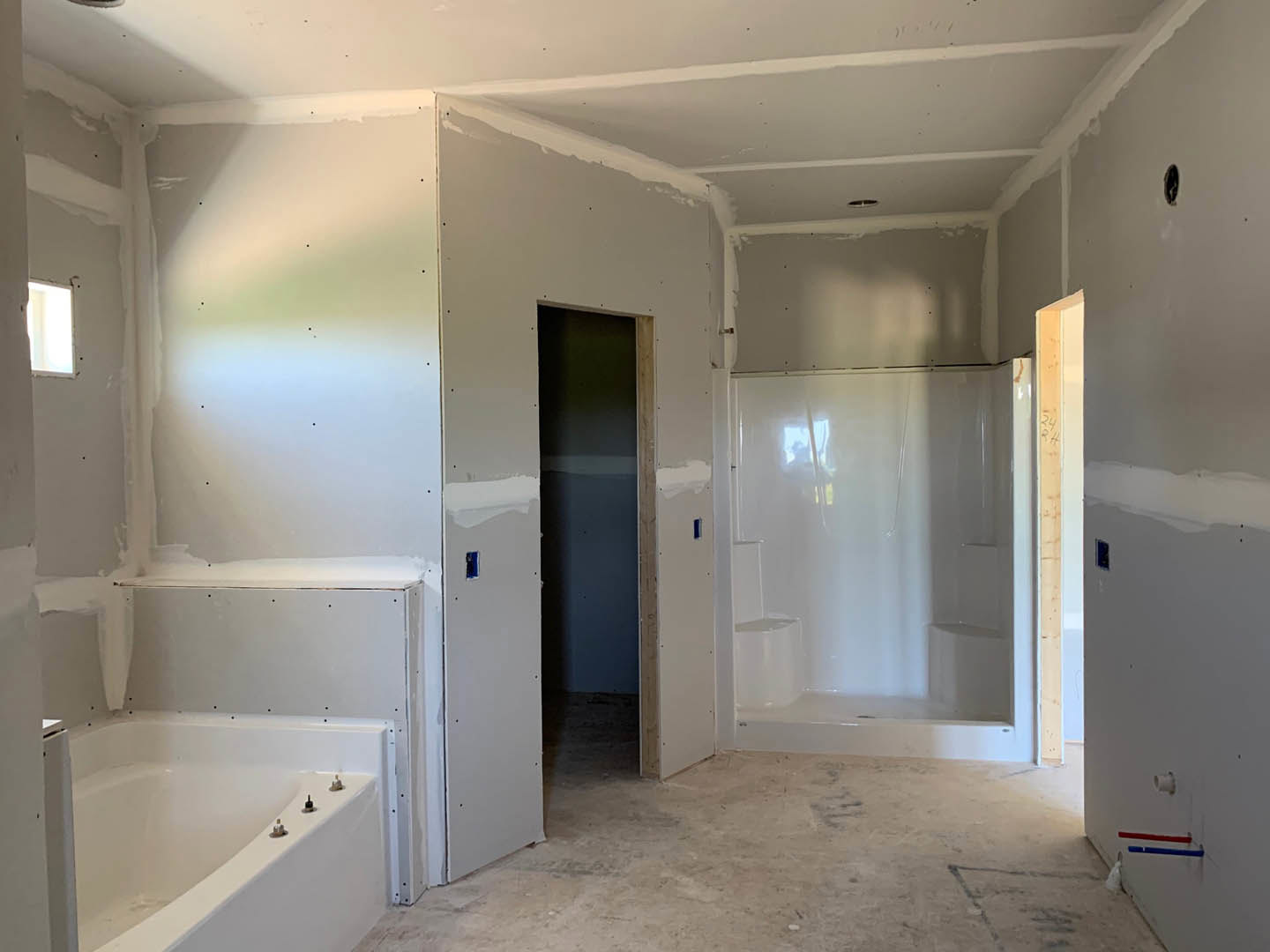 Bathroom with white tile shower, built-in bathtub, blue accent wall, and white trim detailing
