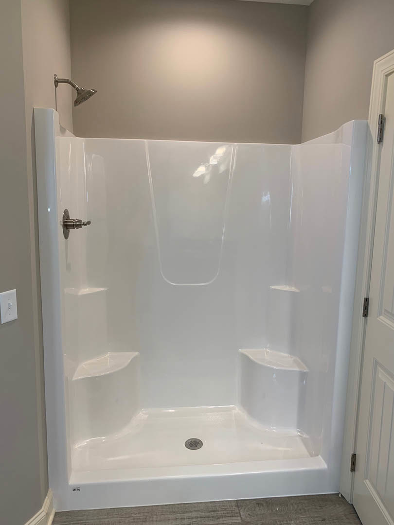 White tiled shower with chrome showerhead and glass enclosure in modern bathroom
