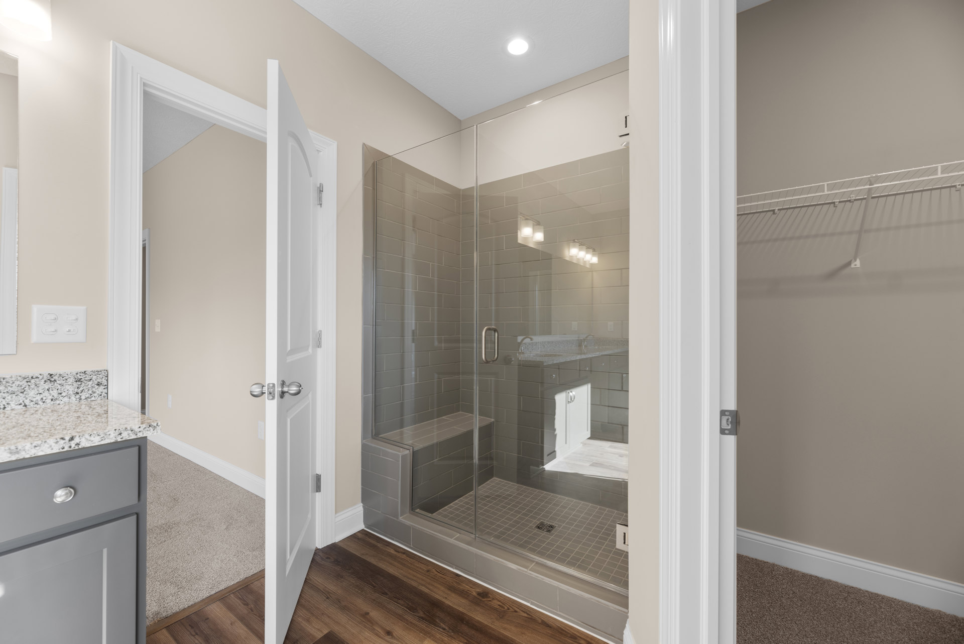Frameless glass shower enclosure with chrome hardware, white tile walls, built-in shelf, and adjacent vanity drawer in modern bathroom