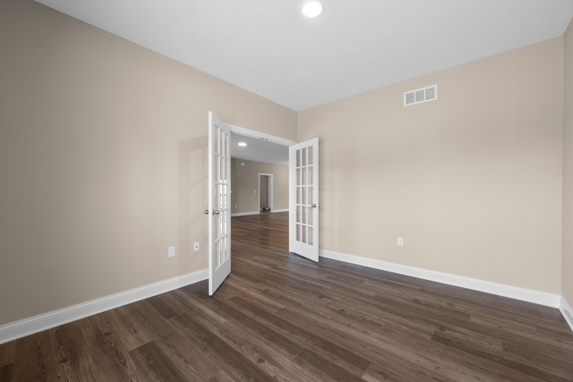 Wood flooring with white paneled doors, white walls, ceiling light fixture, and wall vent in a residential interior room
