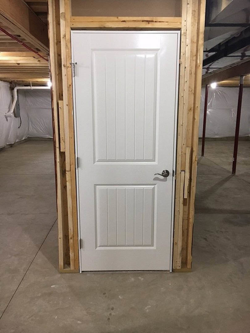 White paneled door with silver handle, wood plank flooring, ceiling pipe, and nearby window in a modern interior room