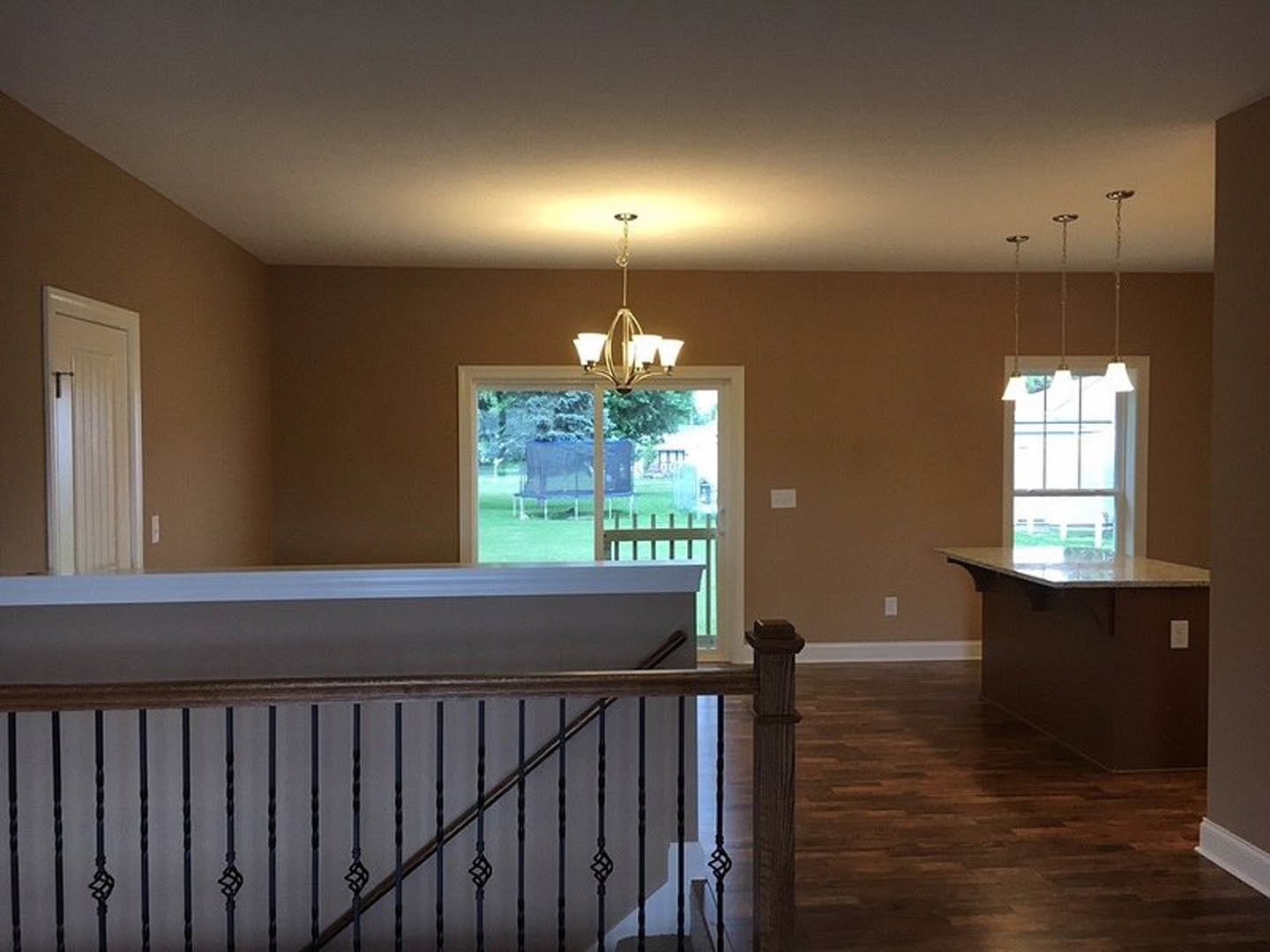 Open-concept living area featuring a wood floor, built-in bar with cabinetry, sliding glass door overlooking backyard, white interior door with chrome handle, stone countertop