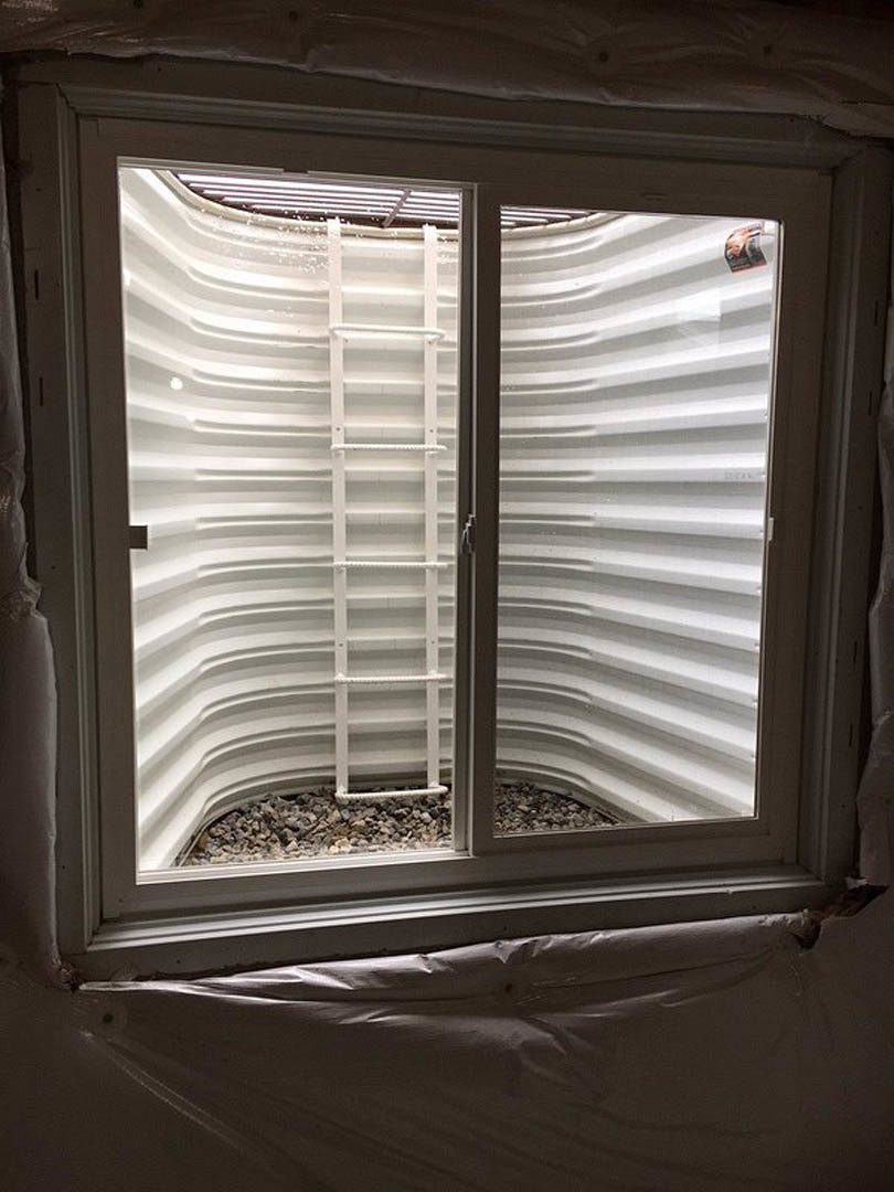 White-framed window with a black sill, white ladder leaning against a white wall, plastic bag resting on the window ledge