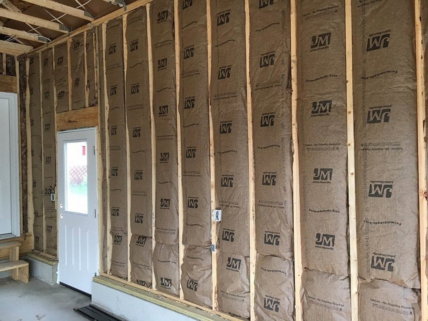 Brown paper bags stacked along an interior wall, white door with window, black and white logo on a sign, exposed ceiling beams