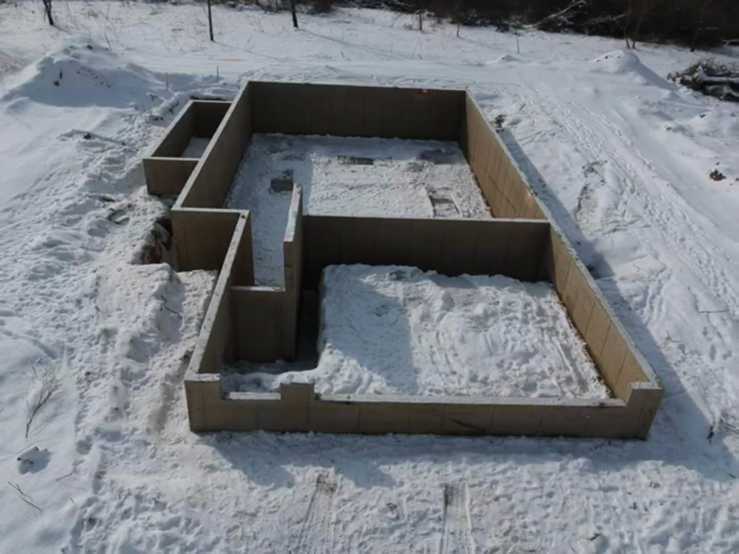 Modern custom home exterior with white brick walls, black trim accents, and snow covering the ground in a winter landscape
