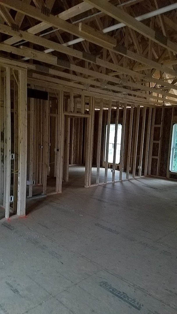 Living room with exposed wood ceiling beams, large window letting in natural light, concrete floor, and neutral walls.