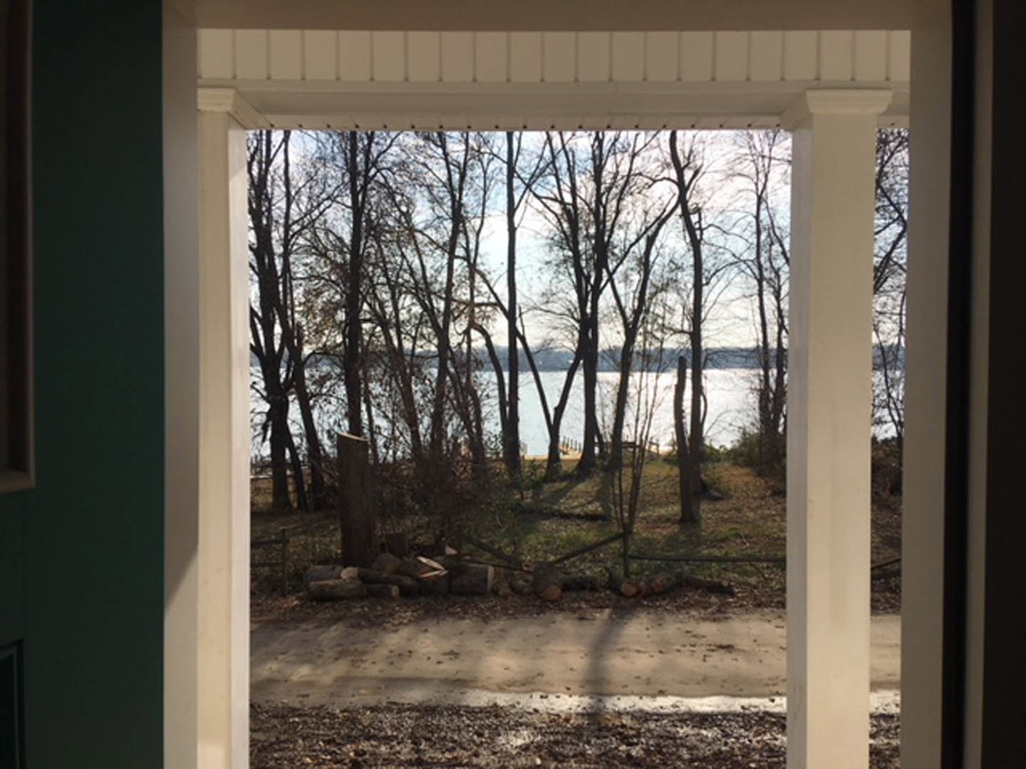 Lake view framed by doorway, with trees, dock, and winter grass visible through exterior opening