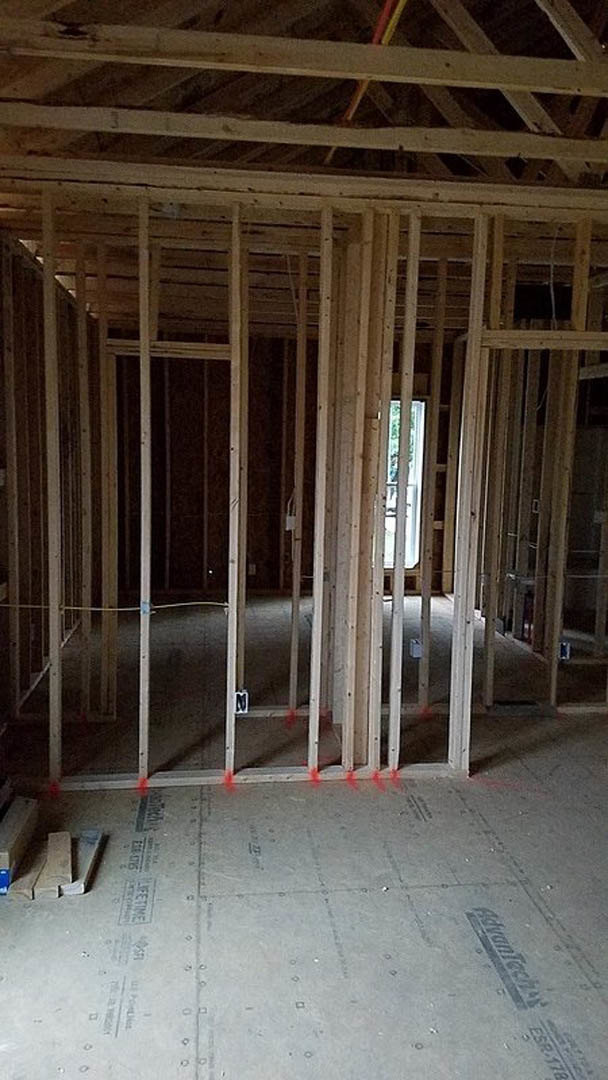 Unfinished room featuring exposed wood framing, ceiling beams, and wall insulation